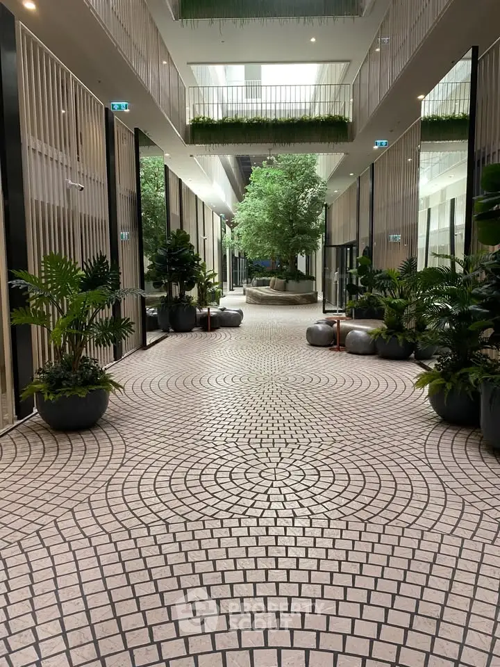 Luxurious modern building entrance with elegant tile flooring and lush greenery.