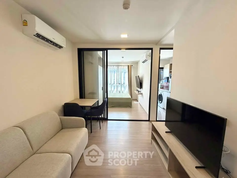 Modern living room with sleek furniture and open layout, featuring a cozy sofa and large TV.