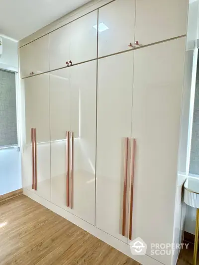 Spacious modern wardrobe with sleek design and ample storage in a bright room with wooden flooring.