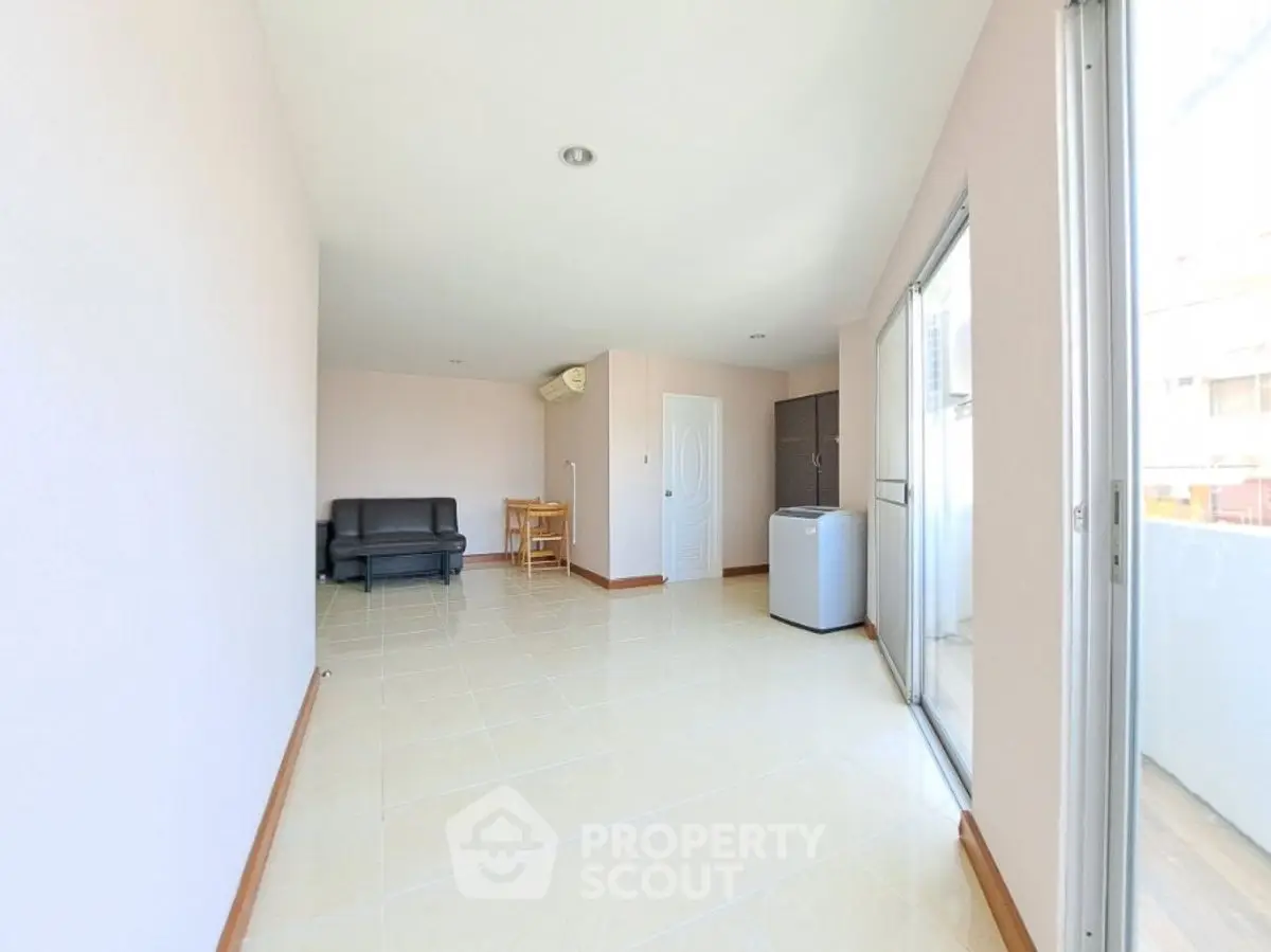 Spacious living room with modern furniture and balcony access in a bright apartment.