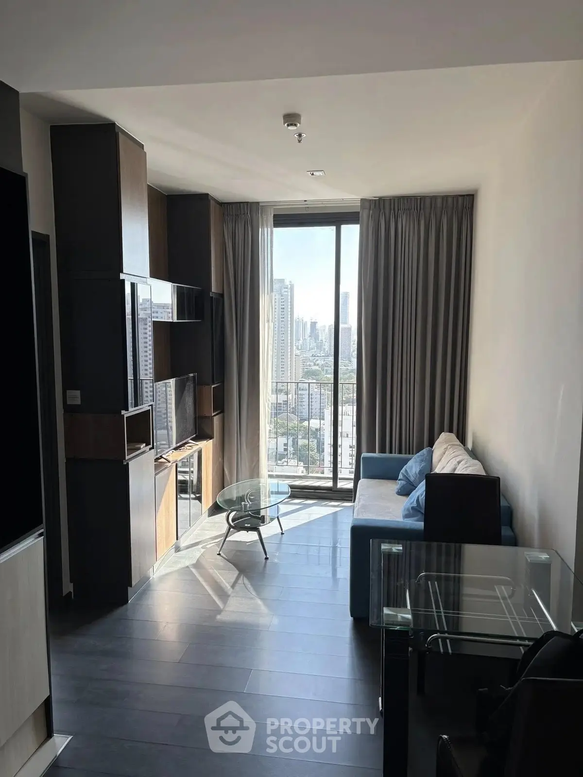 Modern living room with city view, sleek furniture, and floor-to-ceiling windows in urban apartment.