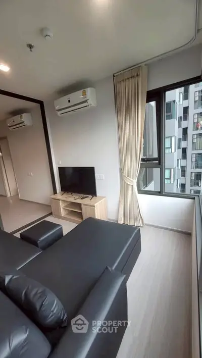 Modern living room with sleek black sofa, air conditioning, and large window offering city view.