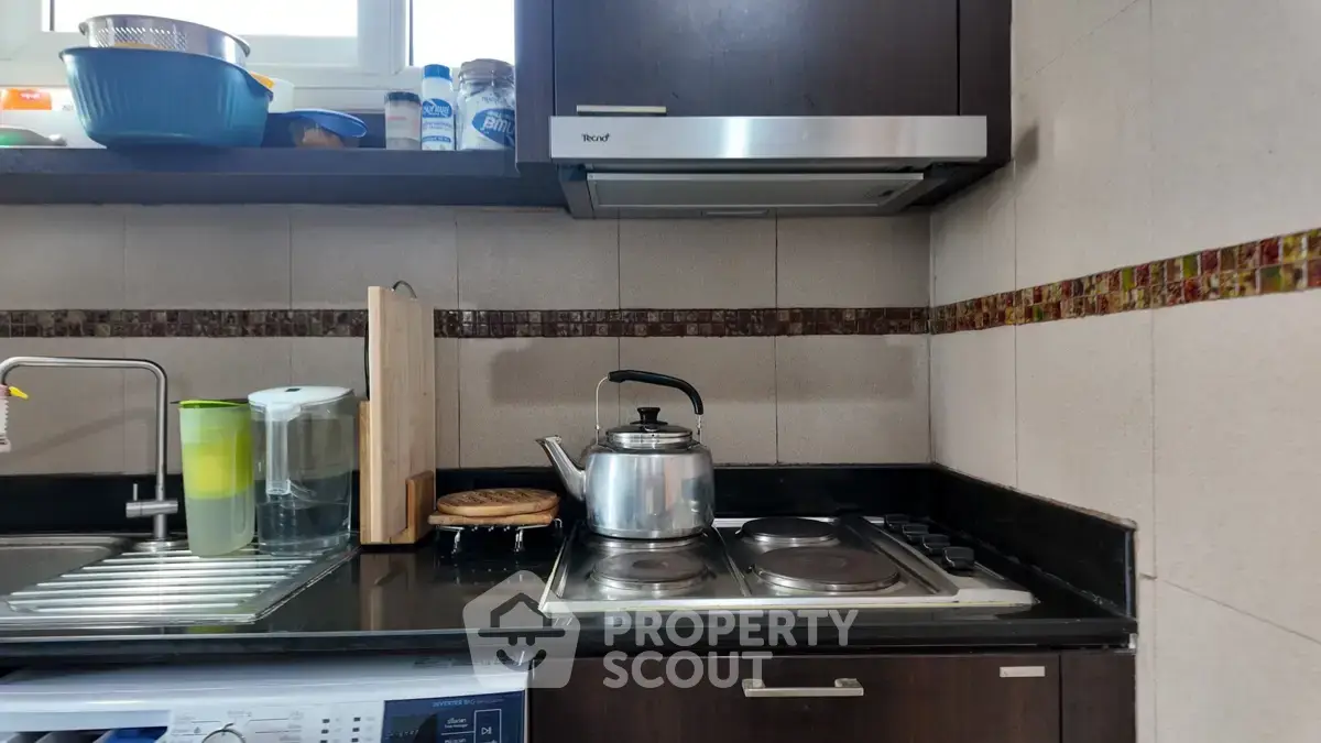 Modern kitchen with sleek appliances and stylish backsplash, featuring a gas stove and ample counter space.