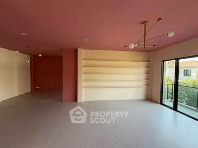 Spacious modern living room with pink accents and large windows offering natural light.