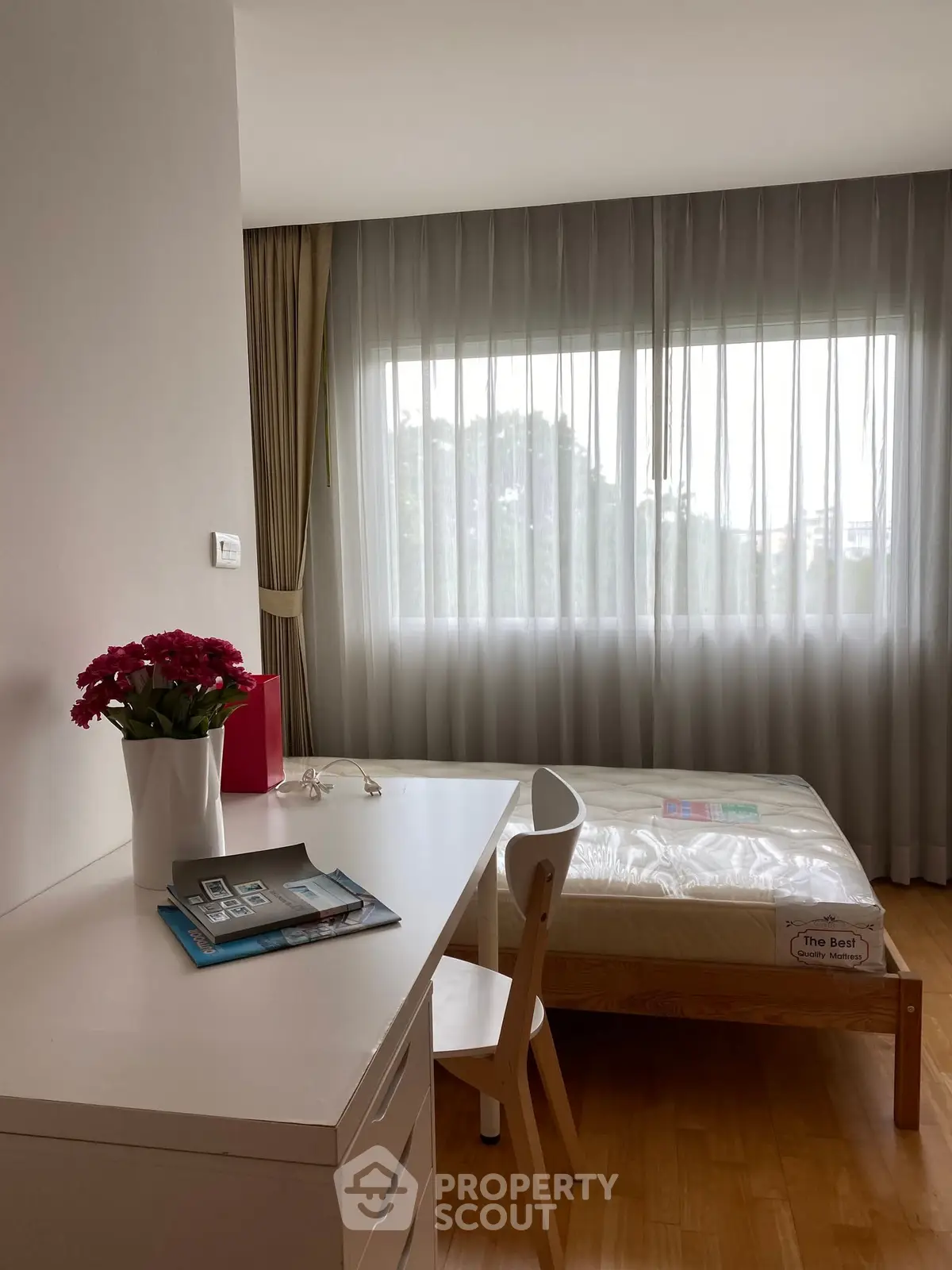 Bright bedroom with large window, wooden flooring, and modern furniture, perfect for a cozy living space.