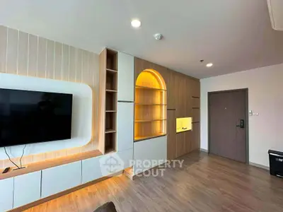 Modern living room with built-in shelving and wall-mounted TV in stylish apartment.