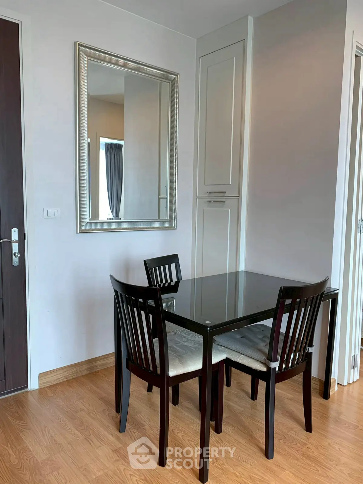 Modern dining area with sleek glass table and elegant chairs in a cozy apartment.
