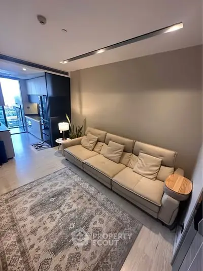 Modern living room with cozy beige sofa and open kitchen layout, featuring stylish decor and natural light.