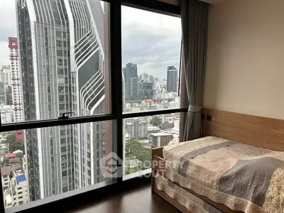 Modern bedroom with stunning city view from floor-to-ceiling windows in high-rise apartment.