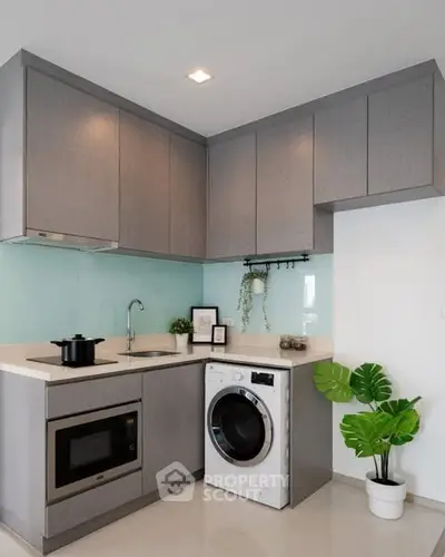 Modern kitchen with sleek cabinets, washing machine, and microwave in a compact layout.