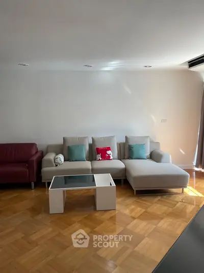 Spacious living room with modern furniture and parquet flooring, perfect for relaxation and entertainment.