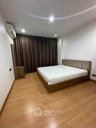 Spacious bedroom with wooden flooring and modern design in a stylish apartment.