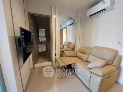 Modern living room with beige leather recliner and wall-mounted TV, featuring sleek air conditioning unit.