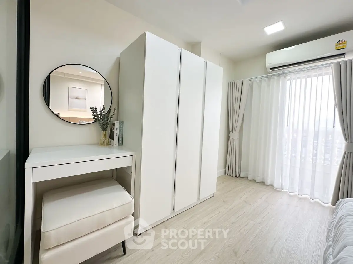 Bright and airy bedroom with modern white furniture and large window view.