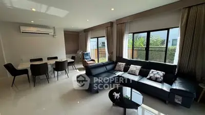 Modern living room with sleek black sofa and dining area, featuring large windows and air conditioning.
