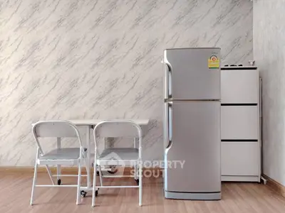 Modern kitchen with sleek fridge and dining area in stylish apartment.