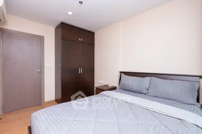 Modern bedroom with sleek wooden wardrobe and cozy bed in a minimalist design.