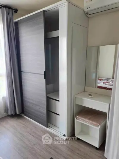 Modern bedroom with sleek wardrobe and vanity set, featuring natural light and elegant design.