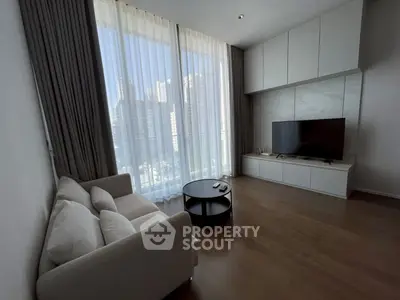 Modern living room with large windows, cozy sofa, and sleek TV setup.