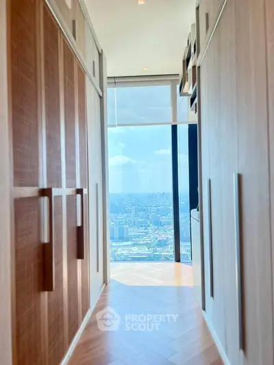 Luxurious hallway with stunning city view through floor-to-ceiling windows, featuring elegant wooden cabinetry.