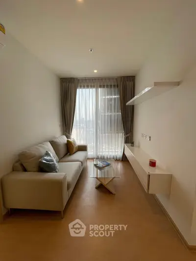 Modern living room with cozy sofa and natural light through large window.