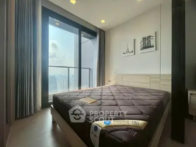 Modern bedroom with large window and city view, featuring a comfortable bed and stylish decor.