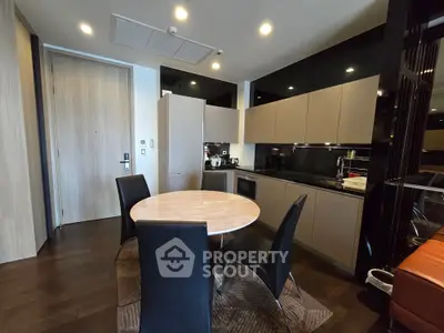 Modern kitchen with sleek black countertops and round dining table in stylish apartment.