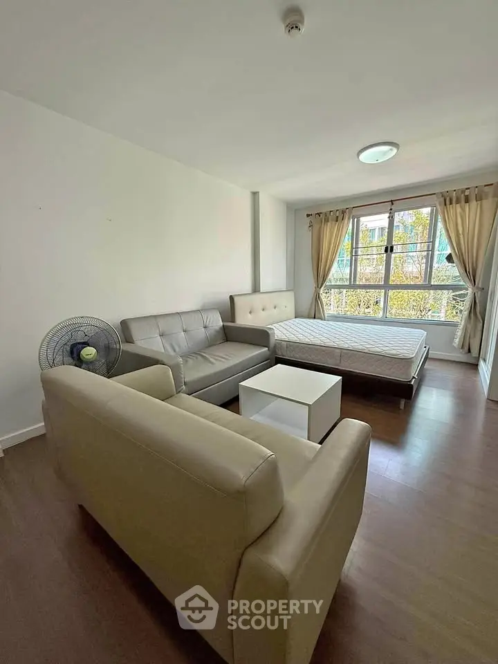 Spacious studio apartment with modern furnishings and large window for natural light.