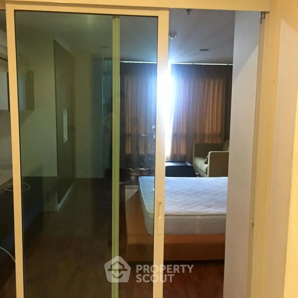 Modern apartment with sliding glass doors separating bedroom and living area.