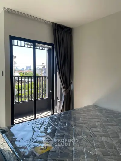 Bright bedroom with balcony access and city view, featuring a comfortable mattress and elegant curtains.