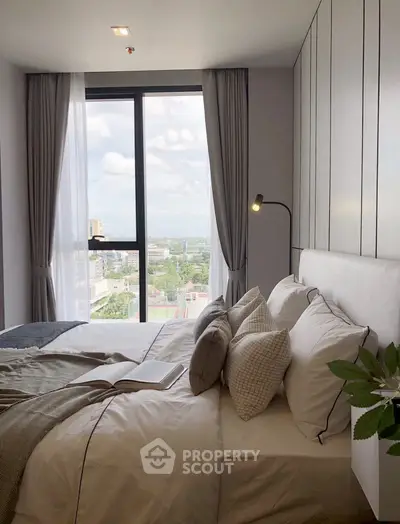 Modern bedroom with large window offering stunning city view, elegant decor, and cozy ambiance.