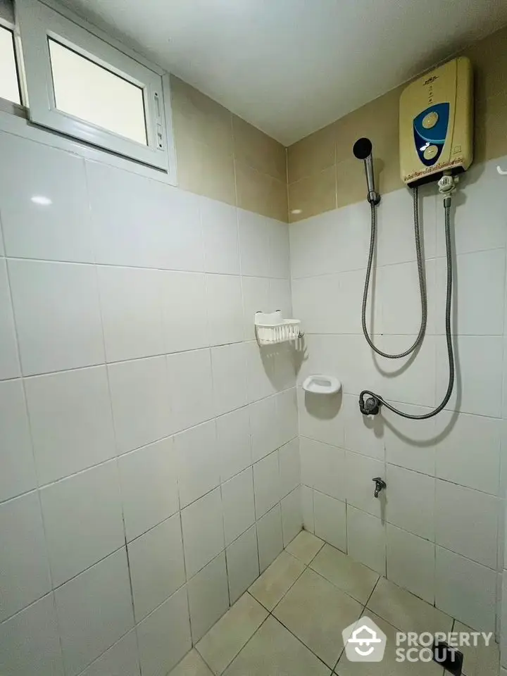 Compact bathroom with tiled walls and electric shower heater