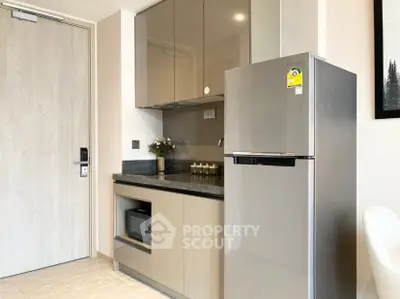 Modern kitchen with sleek cabinets and stainless steel fridge in a stylish apartment.
