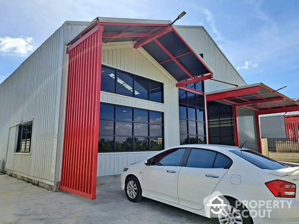 Modern industrial warehouse with red accents and spacious parking area