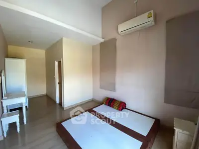 Spacious minimalist bedroom with air conditioning and wooden flooring.