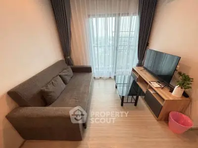 Cozy living room with modern sofa, TV, and balcony view, perfect for relaxation.