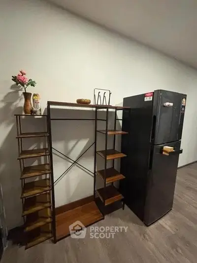 Modern kitchen corner with sleek black fridge and stylish shelving unit.