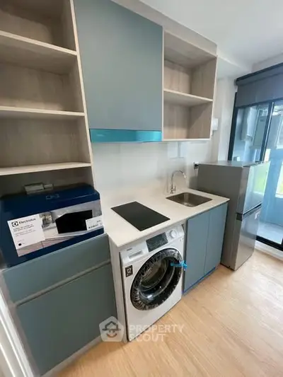 Modern kitchen with sleek cabinetry, washing machine, and compact appliances in a stylish apartment.