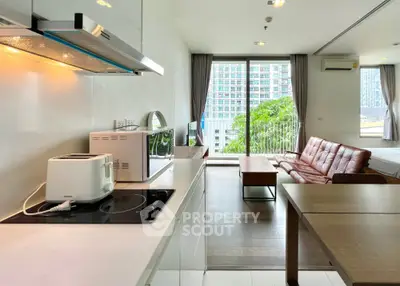 Modern open-plan living area with kitchen and city view balcony in high-rise apartment