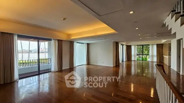 Spacious living room with hardwood floors and large windows offering natural light.