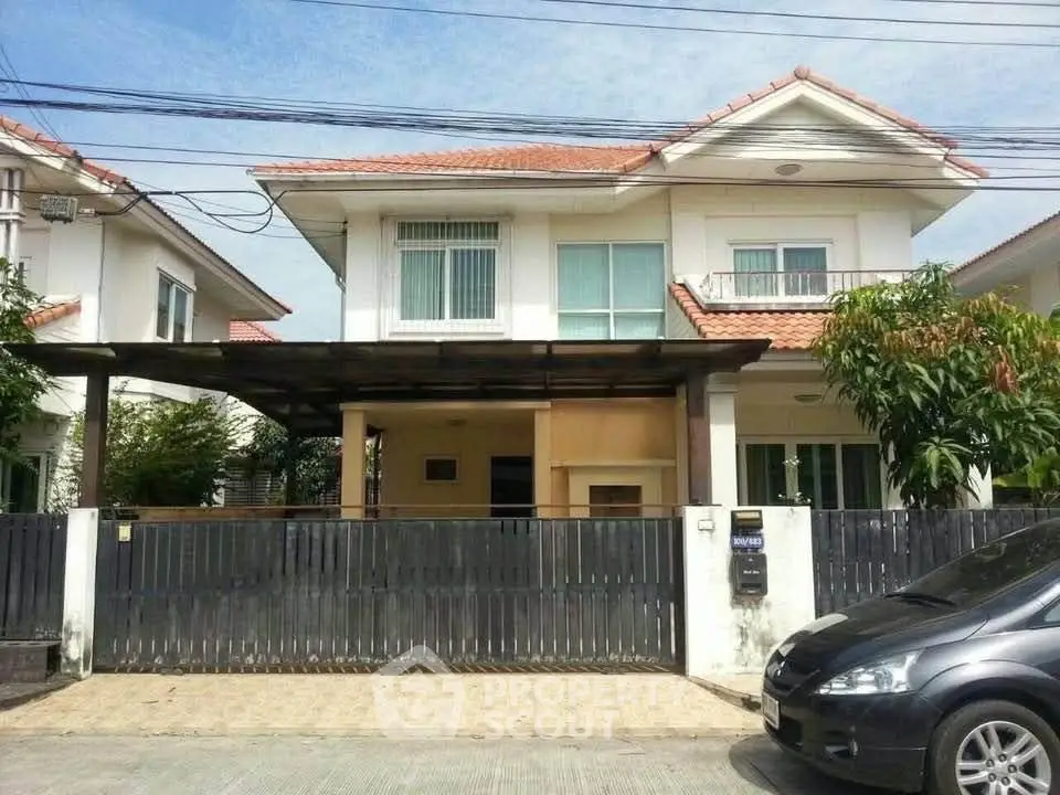 Charming two-story house with a tiled roof and gated driveway in a suburban neighborhood.