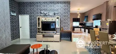 Modern open-plan living room with stylish brick accent wall and sleek kitchen area.