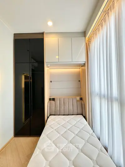 Modern bedroom with sleek design, featuring a single bed and built-in wardrobe with ambient lighting.