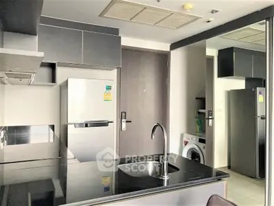 Modern kitchen with sleek appliances and washing machine in stylish apartment.
