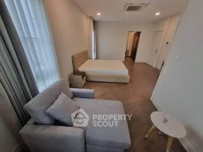 Spacious bedroom with modern decor and cozy seating area in a stylish apartment.