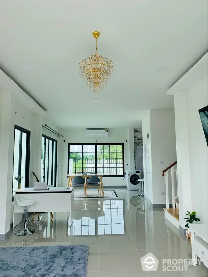 Spacious and bright living area with gleaming floor tiles, elegant chandelier, and modern furnishings, leading to a cozy dining space.