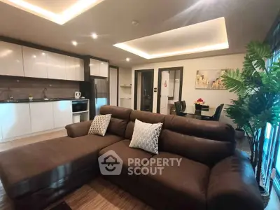 Modern open-layout living room with stylish kitchen and cozy brown sofa, perfect for entertaining.