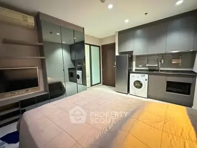 Modern studio apartment with sleek kitchen and cozy bedroom area, featuring built-in appliances and mirrored wardrobe.