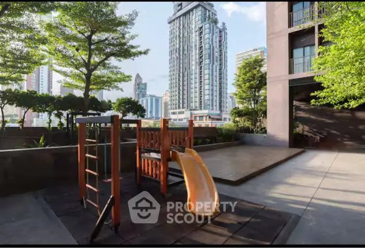 Modern urban playground with slide in residential complex, surrounded by skyscrapers and lush greenery.