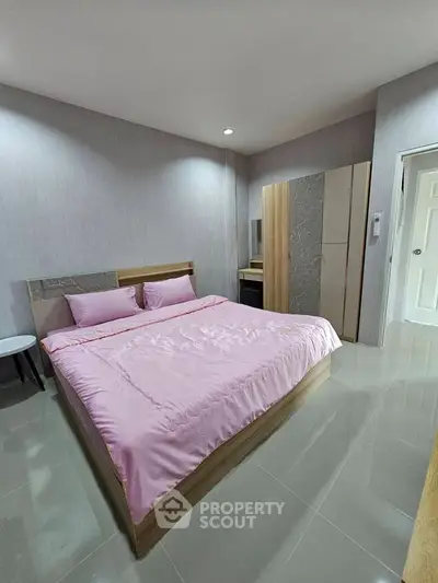 Spacious bedroom with modern decor and pink bedding in a stylish apartment.